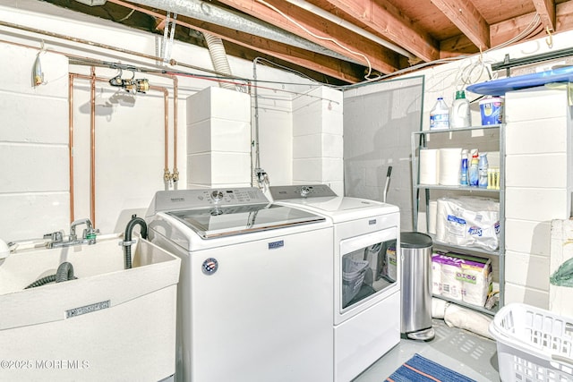 clothes washing area featuring laundry area, washing machine and dryer, and a sink