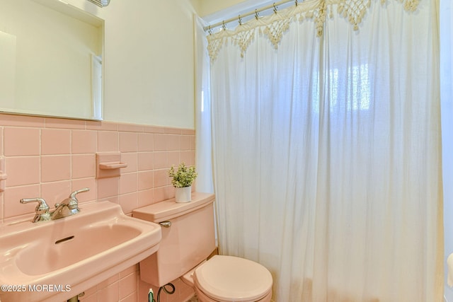 bathroom featuring a sink, a shower with shower curtain, toilet, and tile walls