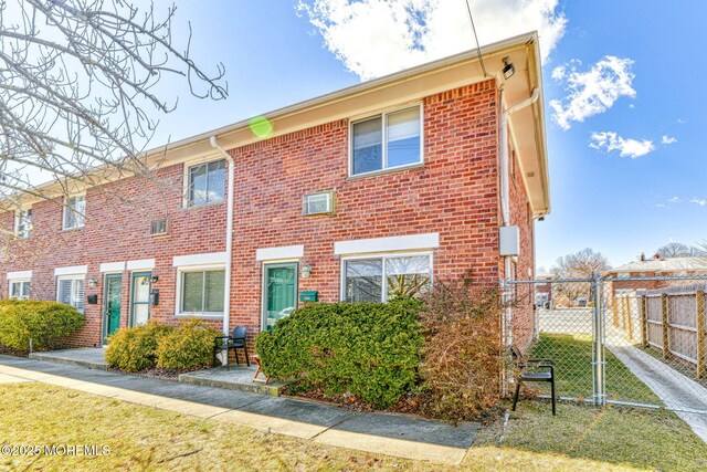 townhome / multi-family property featuring a gate, brick siding, and fence