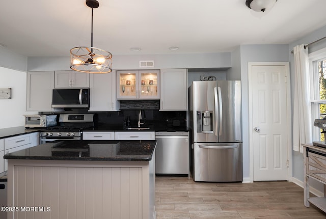 kitchen featuring a chandelier, stainless steel appliances, a sink, tasteful backsplash, and pendant lighting