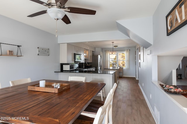 dining space featuring a toaster, visible vents, dark wood-type flooring, ceiling fan, and baseboards