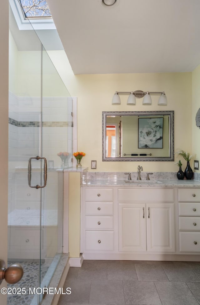 bathroom with a skylight, a shower stall, and vanity