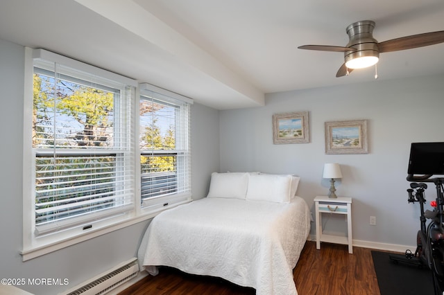 bedroom with a baseboard heating unit, dark wood finished floors, and baseboards