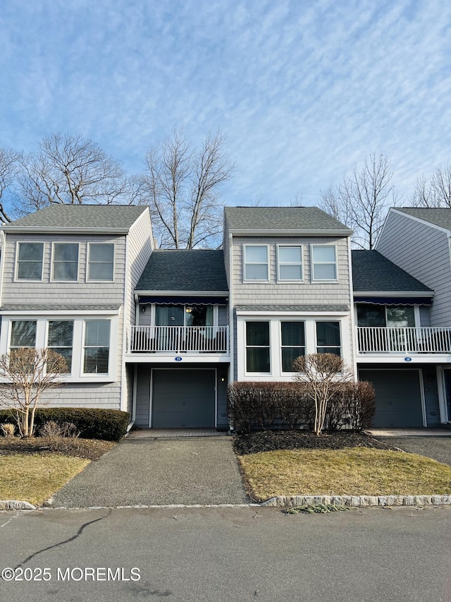 view of front facade with aphalt driveway, an attached garage, and roof with shingles