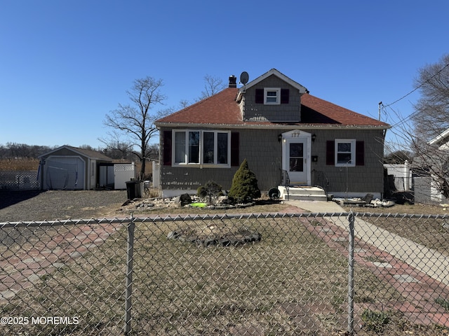 bungalow-style home featuring an outbuilding, a shed, a fenced front yard, and a shingled roof