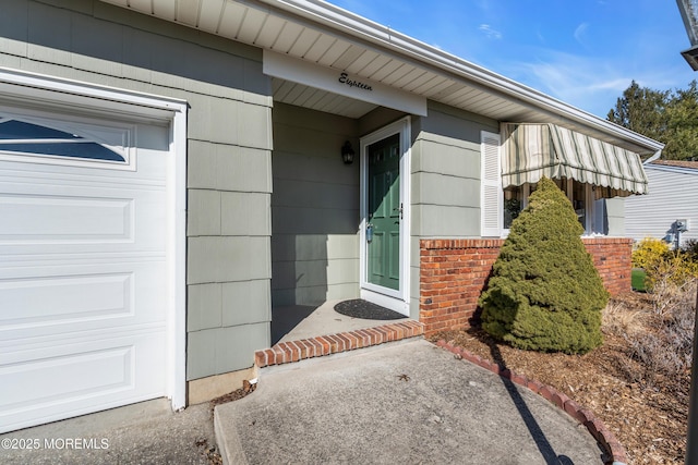 doorway to property featuring brick siding and an attached garage