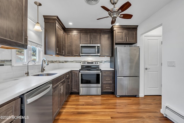 kitchen with a sink, a baseboard radiator, dark brown cabinetry, and appliances with stainless steel finishes