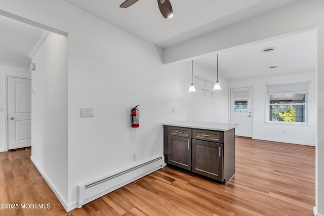 kitchen with dark brown cabinets, a peninsula, light wood-type flooring, and a baseboard radiator