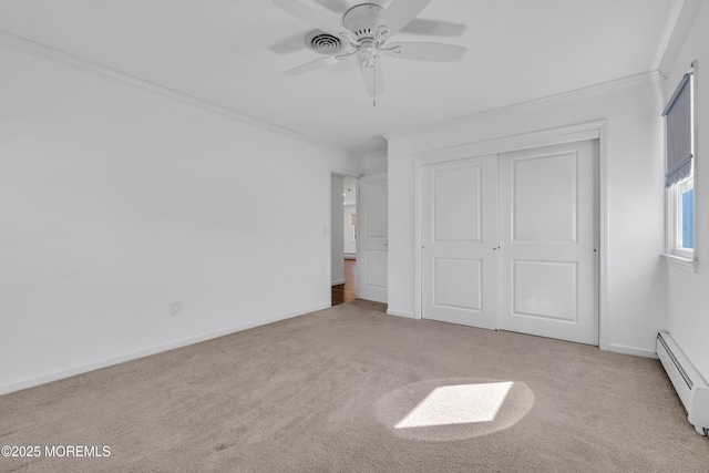 unfurnished bedroom with a baseboard heating unit, a closet, carpet, crown molding, and baseboards