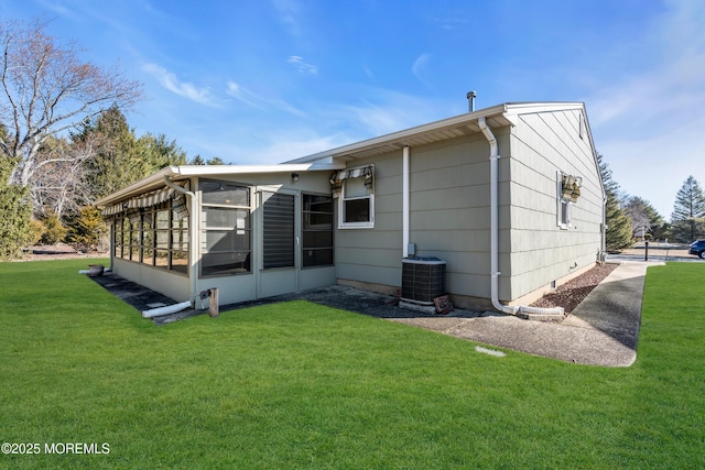 rear view of house featuring central air condition unit, a yard, and a sunroom