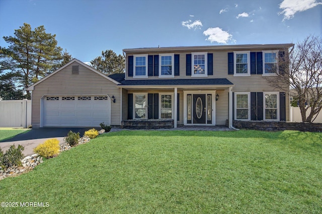 colonial-style house with an attached garage, aphalt driveway, fence, and a front lawn