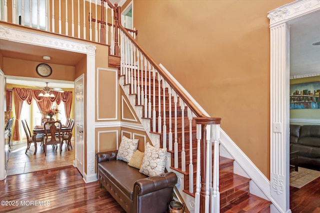 stairs featuring a high ceiling, baseboards, a chandelier, and wood finished floors