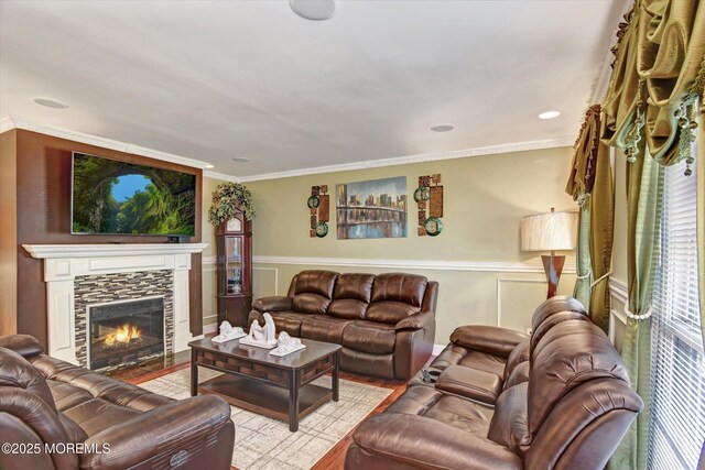 living room with wainscoting, wood finished floors, crown molding, and a tile fireplace