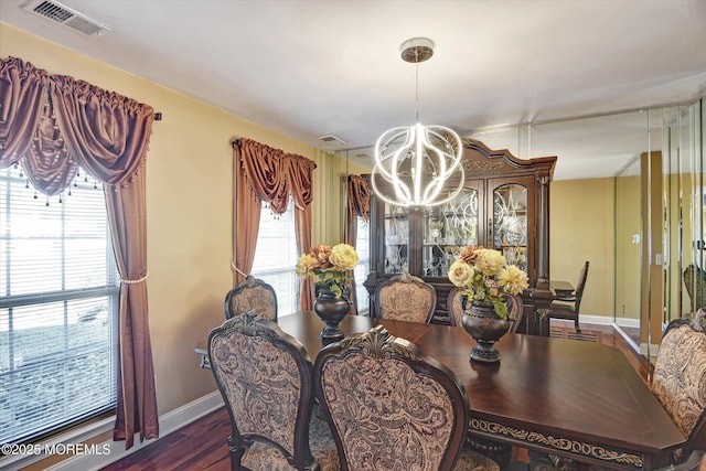 dining area featuring an inviting chandelier, baseboards, visible vents, and wood finished floors