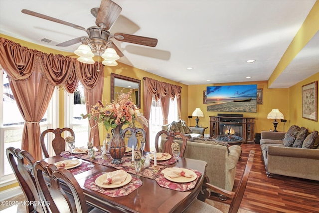 dining room with recessed lighting, visible vents, a ceiling fan, a glass covered fireplace, and wood finished floors