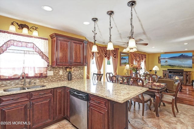 kitchen featuring light stone counters, decorative backsplash, stainless steel dishwasher, a sink, and a peninsula