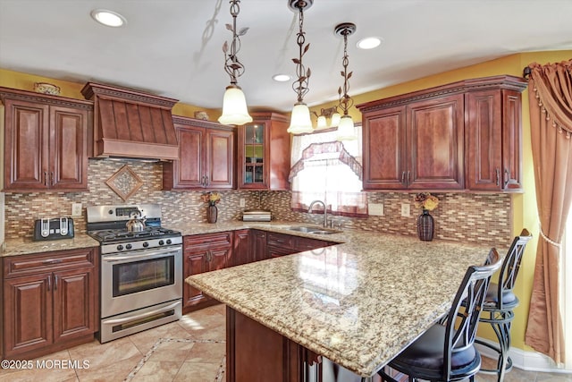 kitchen featuring decorative light fixtures, a peninsula, a sink, custom exhaust hood, and stainless steel range with gas stovetop