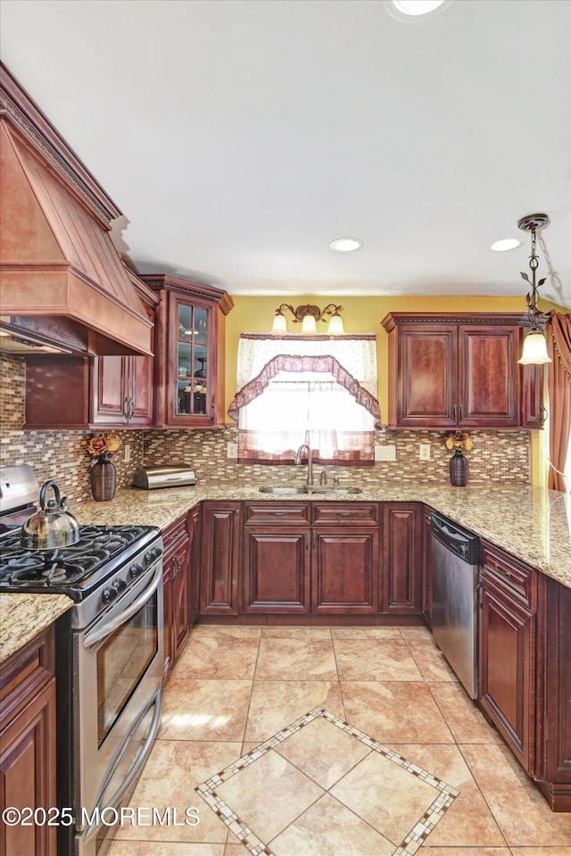 kitchen featuring tasteful backsplash, premium range hood, stainless steel appliances, and a sink