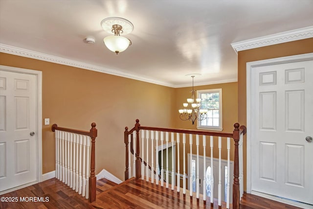 staircase with an inviting chandelier, crown molding, baseboards, and wood finished floors