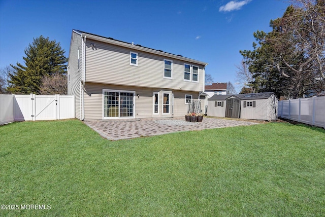 back of house with an outbuilding, a lawn, a gate, a patio area, and a fenced backyard