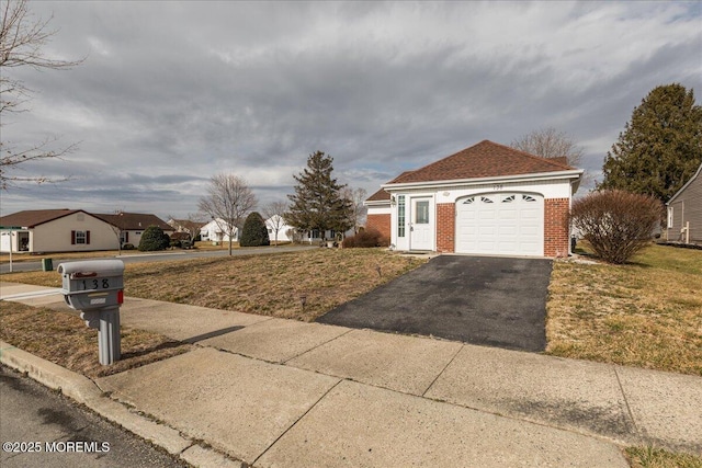 view of front of house featuring a garage, brick siding, driveway, and a front lawn