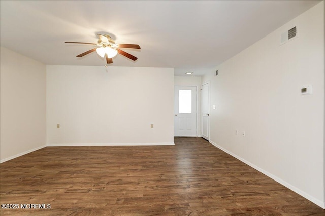 unfurnished room with ceiling fan, dark wood-type flooring, visible vents, and baseboards