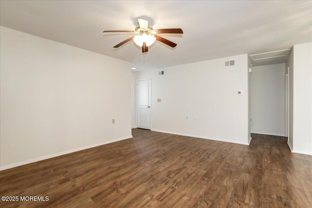 spare room with dark wood-style floors, baseboards, visible vents, and a ceiling fan