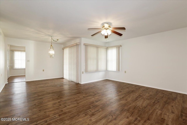 spare room featuring dark wood-style floors, baseboards, and ceiling fan with notable chandelier