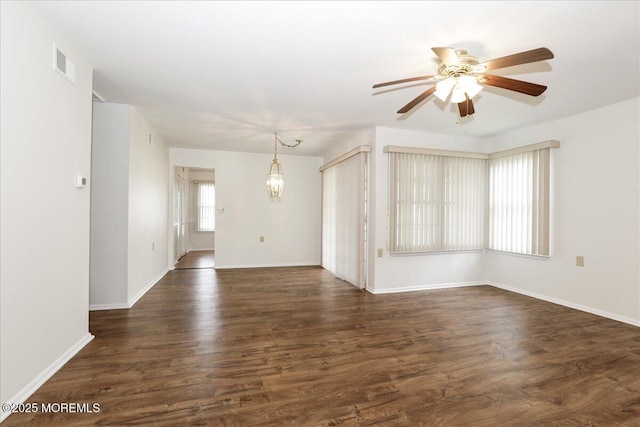 empty room with baseboards, visible vents, wood finished floors, and ceiling fan with notable chandelier