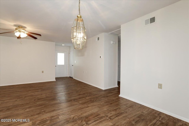 spare room featuring dark wood-type flooring, visible vents, and baseboards