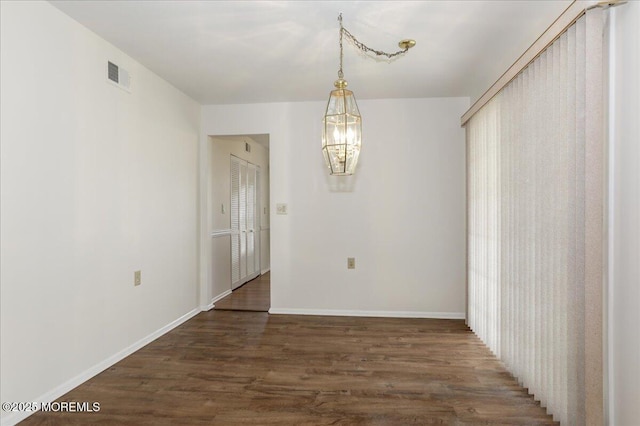 unfurnished dining area with baseboards, visible vents, a chandelier, and dark wood-type flooring