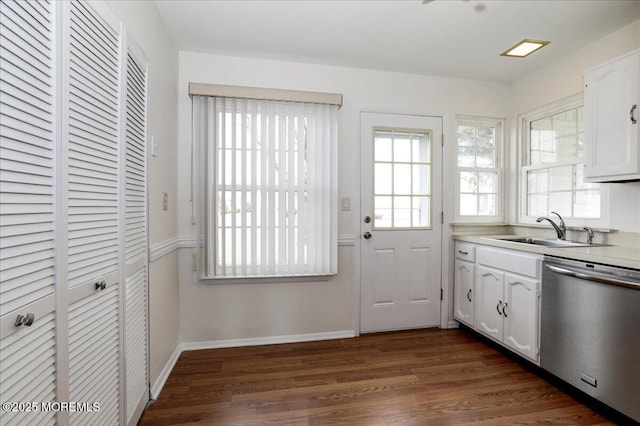 kitchen with baseboards, dark wood-style floors, stainless steel dishwasher, white cabinetry, and a sink