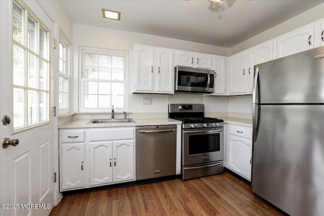 kitchen with appliances with stainless steel finishes, dark wood-type flooring, a sink, and white cabinets