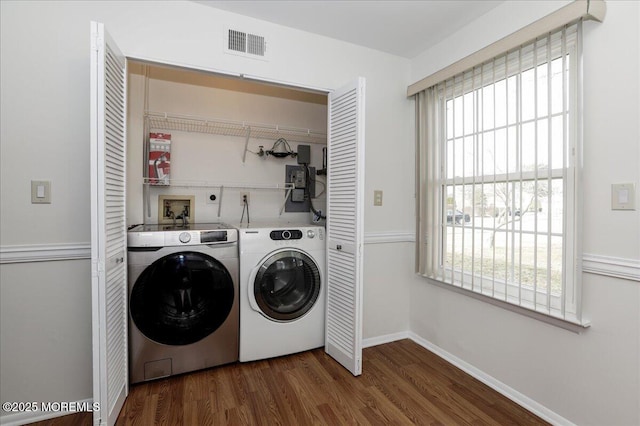 washroom featuring laundry area, baseboards, visible vents, washer and clothes dryer, and wood finished floors