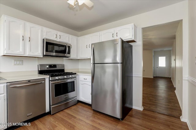 kitchen featuring appliances with stainless steel finishes, white cabinets, wood finished floors, and light countertops