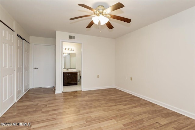 unfurnished bedroom featuring ceiling fan, light wood-style flooring, visible vents, baseboards, and ensuite bath