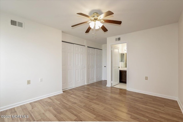 unfurnished bedroom with baseboards, multiple closets, visible vents, and light wood-style floors