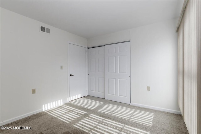 unfurnished bedroom featuring a closet, visible vents, light carpet, and baseboards