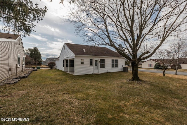 rear view of property featuring a yard and central air condition unit