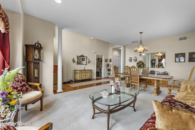 living area with a chandelier, carpet floors, visible vents, and ornate columns