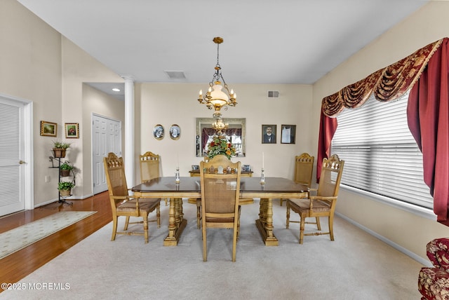 carpeted dining room featuring ornate columns, baseboards, visible vents, and a chandelier