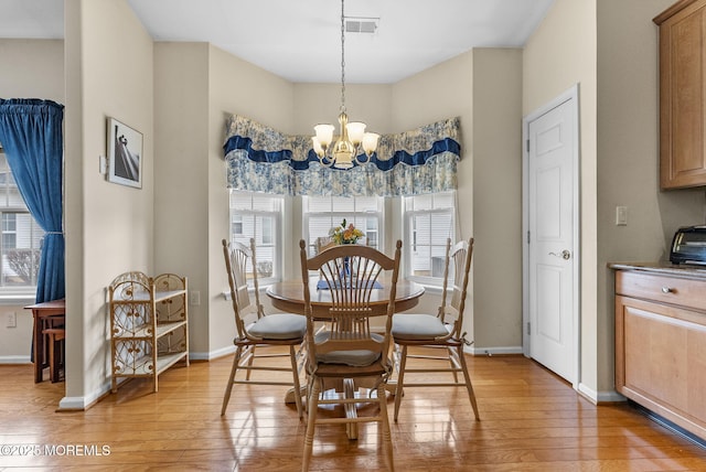 dining area with baseboards, light wood finished floors, visible vents, and a notable chandelier