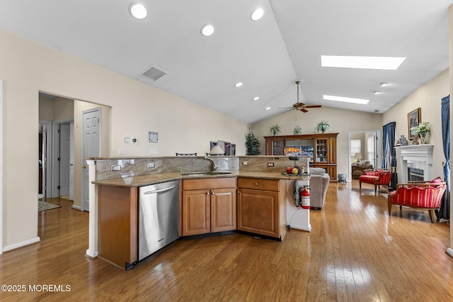 kitchen with visible vents, open floor plan, stainless steel dishwasher, a fireplace, and a sink