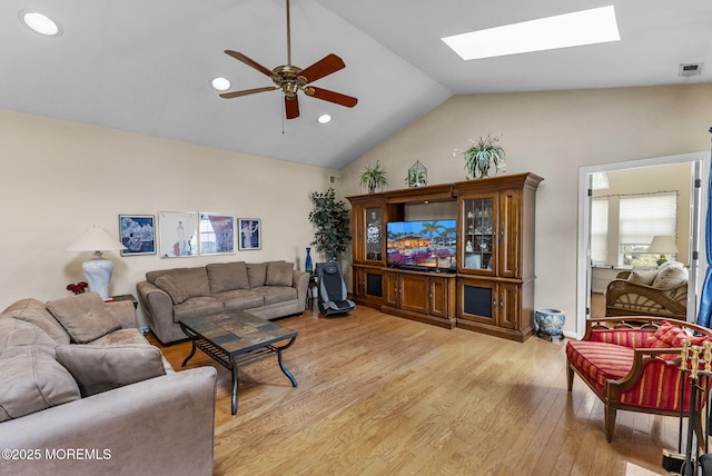 living area with vaulted ceiling with skylight, visible vents, ceiling fan, light wood-style floors, and recessed lighting