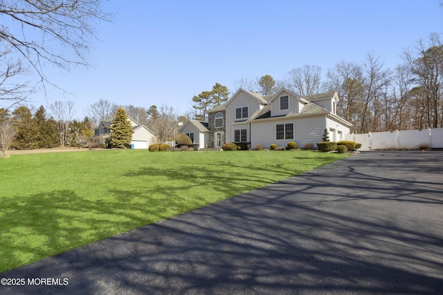 view of front of property with aphalt driveway, a front yard, and fence