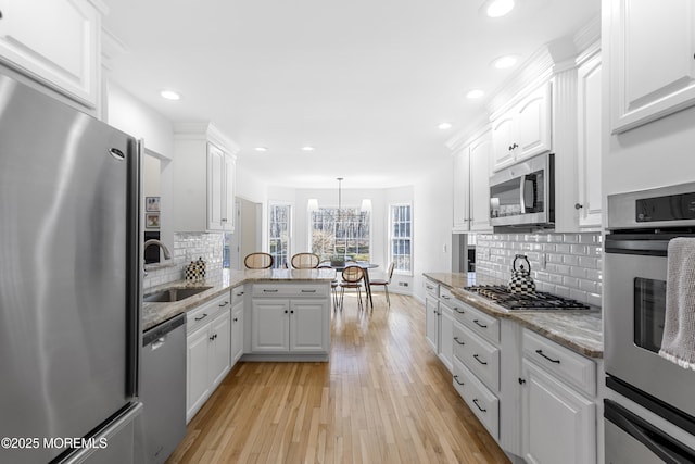 kitchen with white cabinetry, appliances with stainless steel finishes, a sink, and a warming drawer