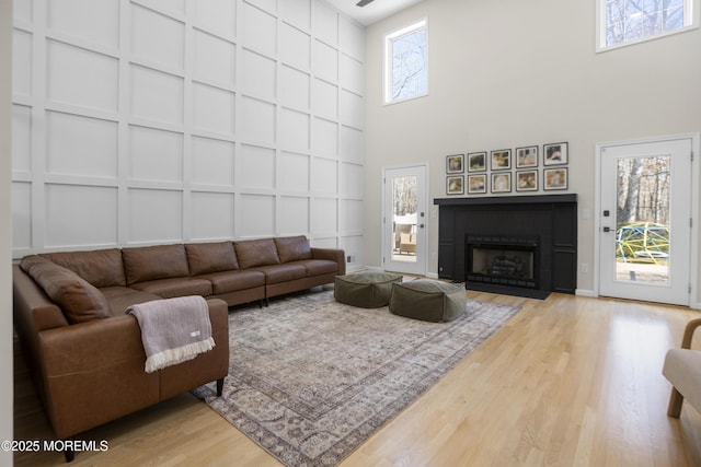 living room with plenty of natural light, a fireplace, a decorative wall, and wood finished floors