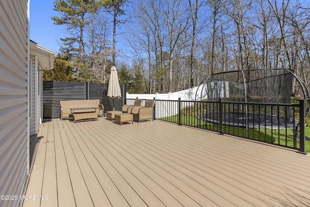 wooden terrace featuring a trampoline and fence