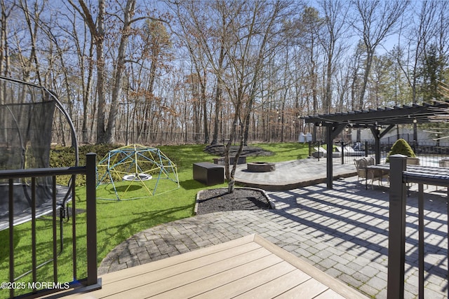 wooden deck with a patio, an outdoor fire pit, a playground, a lawn, and a pergola