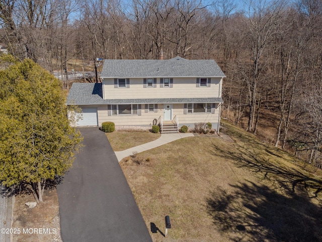 view of front of property featuring a front lawn, driveway, a shingled roof, a garage, and a chimney